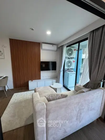 Modern living room with cozy sofa, wall-mounted TV, and balcony access in stylish apartment.