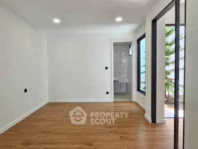 Spacious modern living room with wooden flooring and large windows offering natural light.
