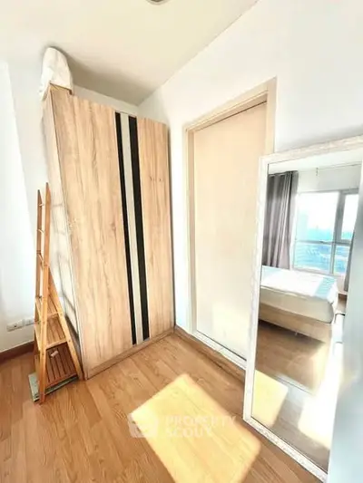 Bright bedroom with wooden wardrobe and large mirror reflecting natural light.