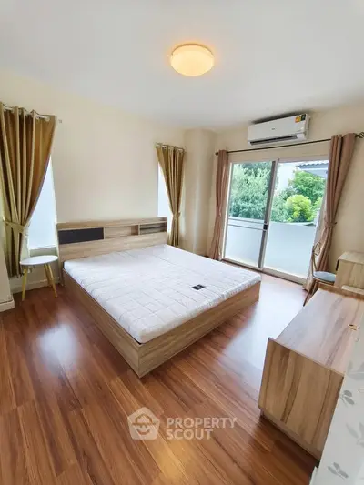 Spacious bedroom with wooden flooring and balcony view