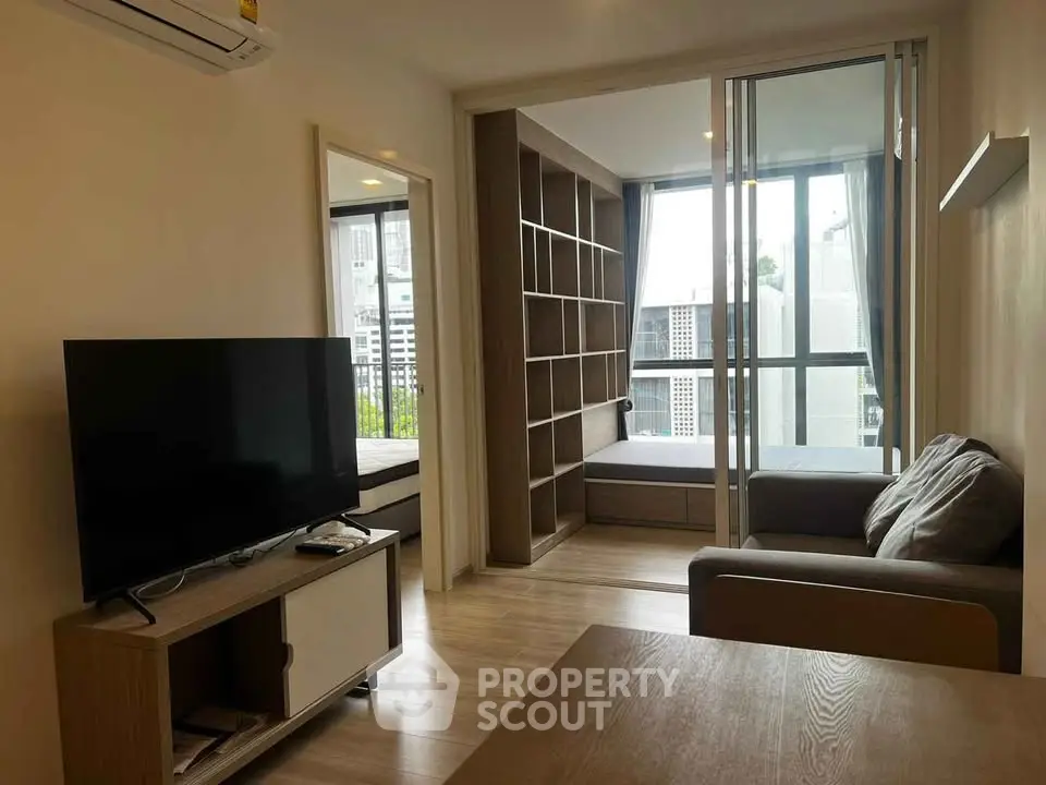Modern living room with TV, sofa, and large window view in stylish apartment.