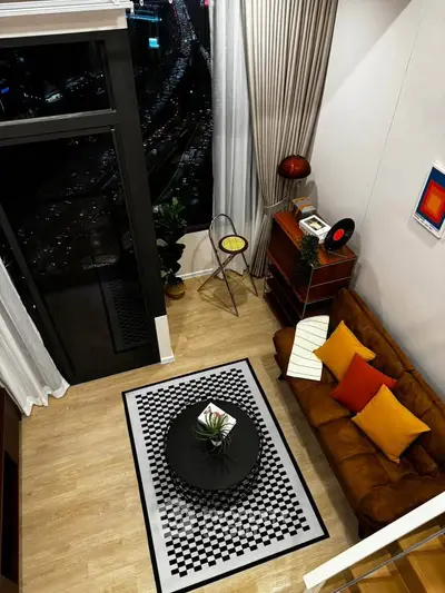Stylish modern living room with high ceiling and city view, featuring chic decor and cozy seating area.