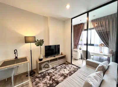 Modern living room with cozy decor and natural light, featuring a stylish workspace and comfortable seating.