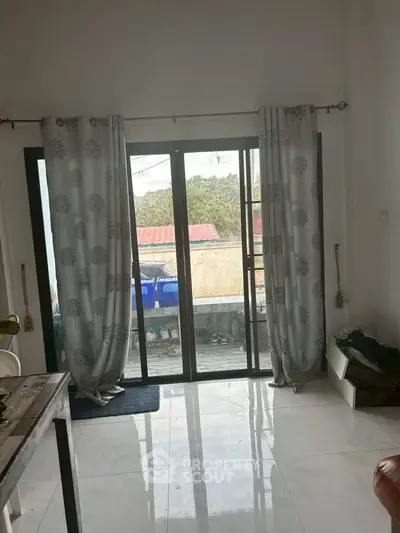 Bright living room with large sliding glass doors leading to a balcony with outdoor view.