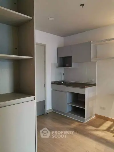 Modern compact kitchen with sleek cabinetry and wood flooring in a cozy apartment.