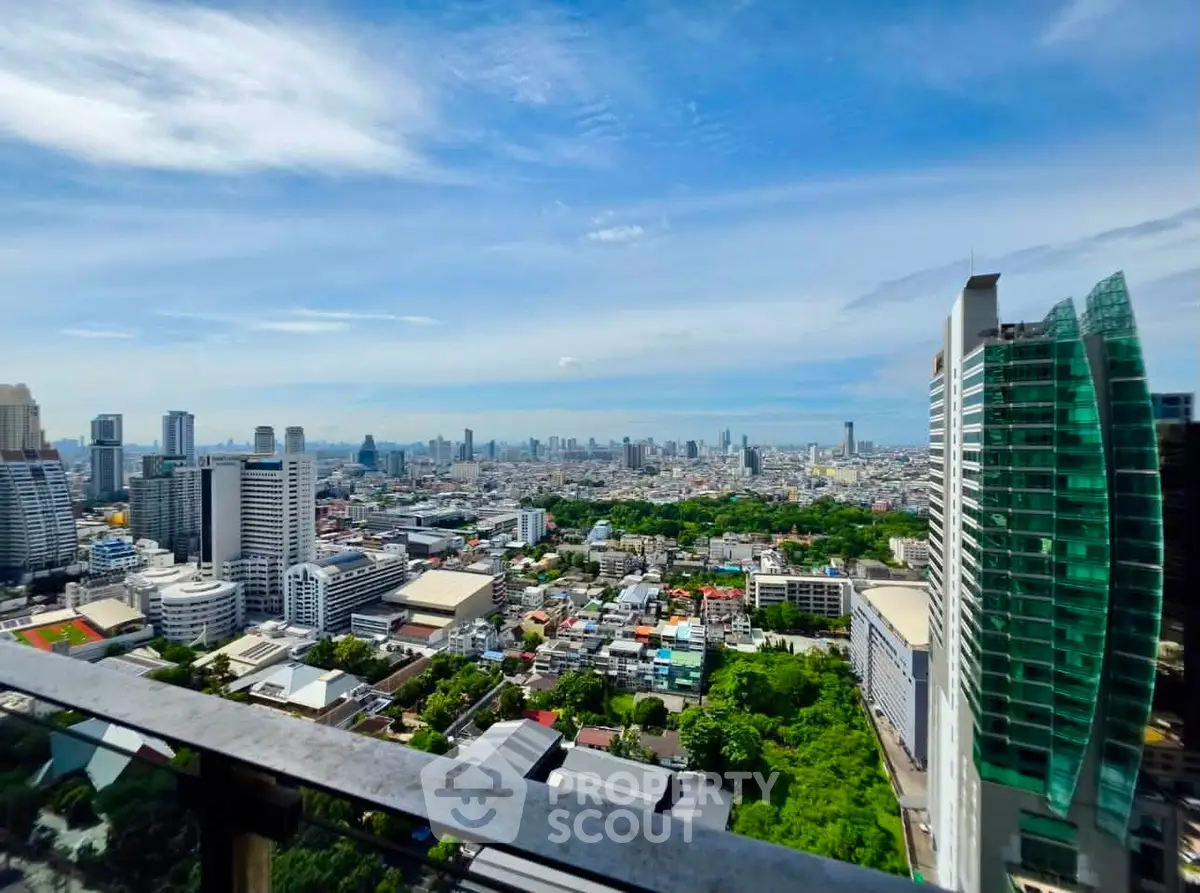 Stunning cityscape view from high-rise balcony with lush greenery and modern architecture.