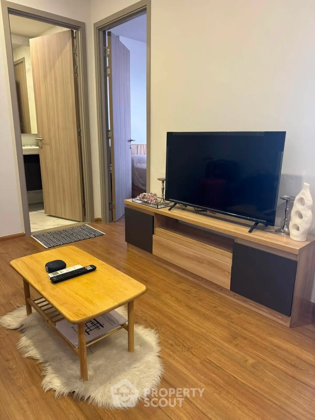 Cozy living room with modern TV setup and wooden flooring, perfect for relaxation.