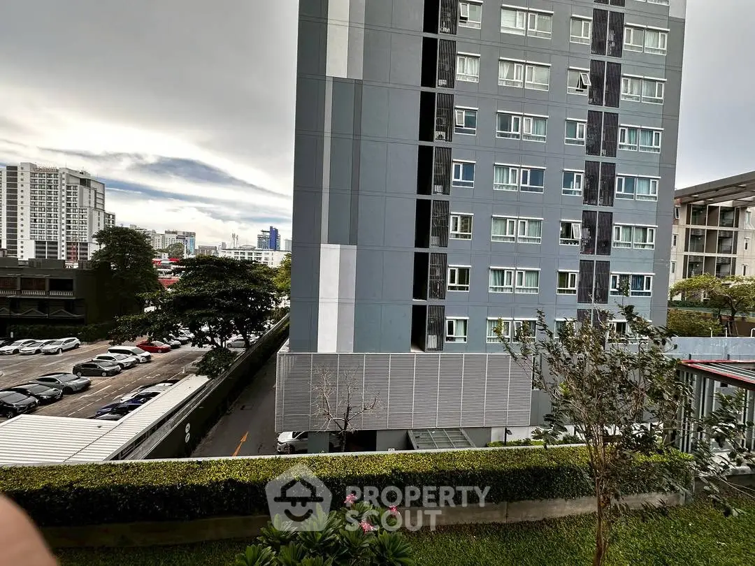 Modern high-rise apartment building with urban view and lush greenery.