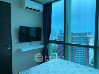 Modern bedroom with city view, featuring large windows, wall-mounted TV, and air conditioning.