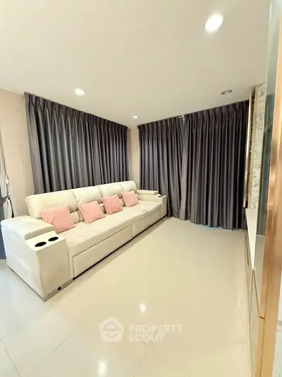 Spacious living room with elegant curtains and cozy sofa, perfect for relaxation.