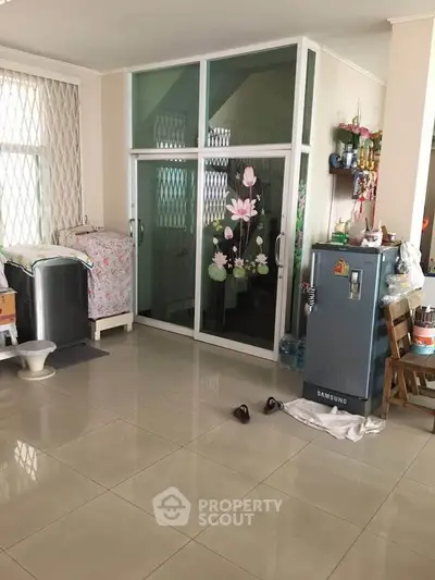 Spacious interior with tiled flooring and glass partition, featuring modern appliances and natural light.