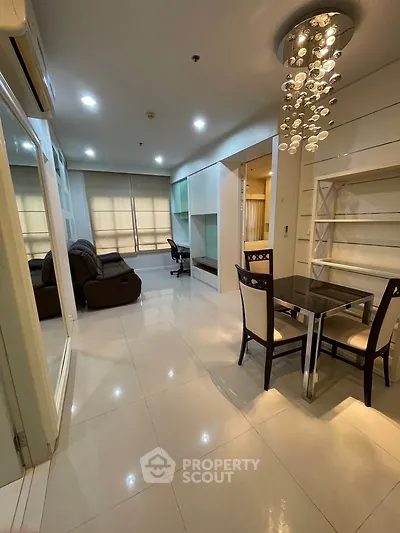 Modern living room with elegant chandelier and dining area in a stylish apartment.