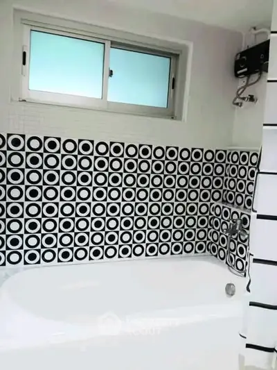 Stylish bathroom with modern black and white circular tile design and bathtub.