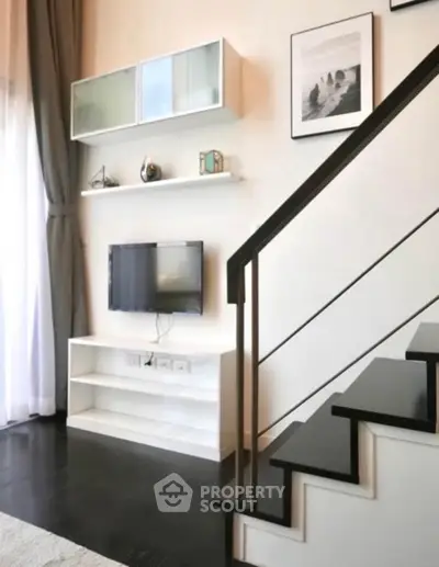 Modern living room with stylish staircase and wall-mounted TV in a contemporary home.