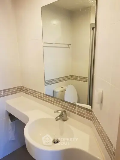 Modern bathroom with sleek sink and large mirror in a stylish apartment.