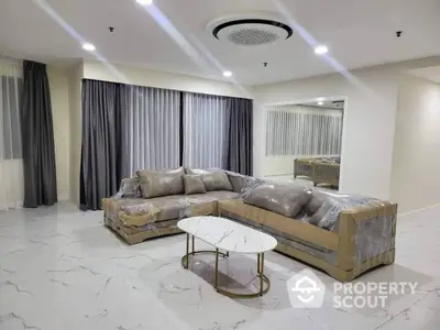 Spacious and elegant living room with luxurious marble flooring, plush sectional sofa, and modern lighting, perfect for upscale living.