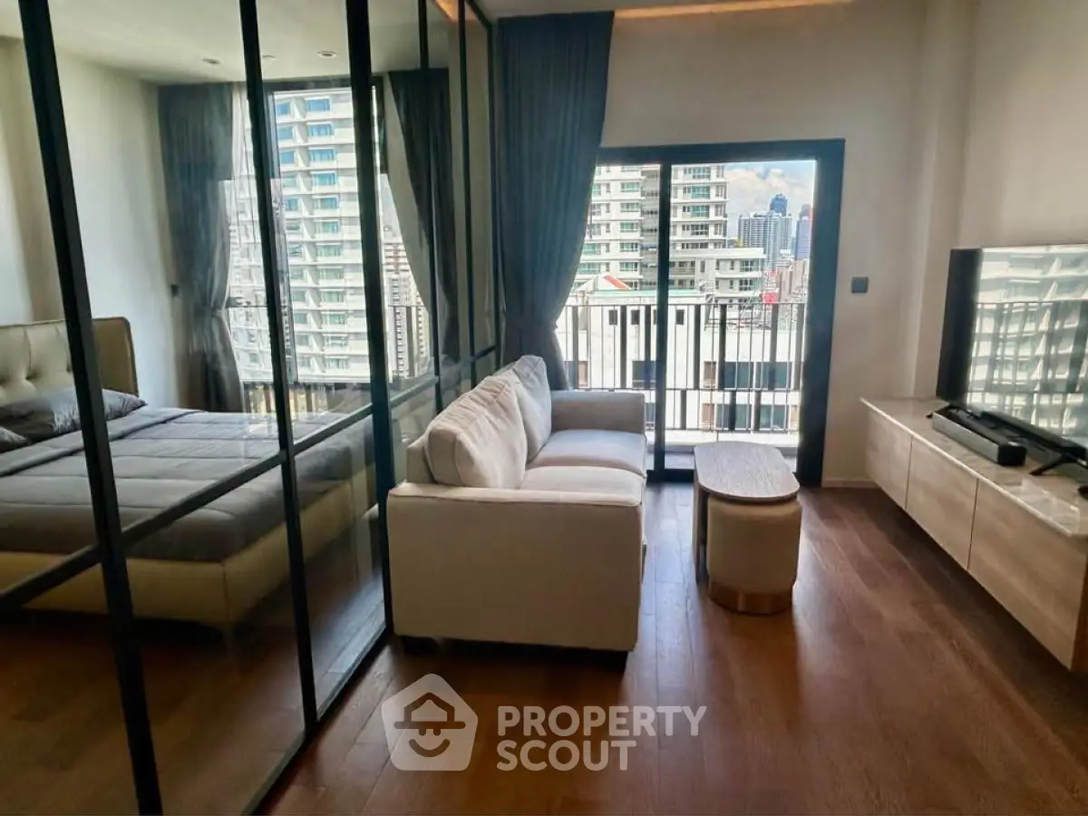 Modern living room with glass wall, cozy sofa, and city view balcony.