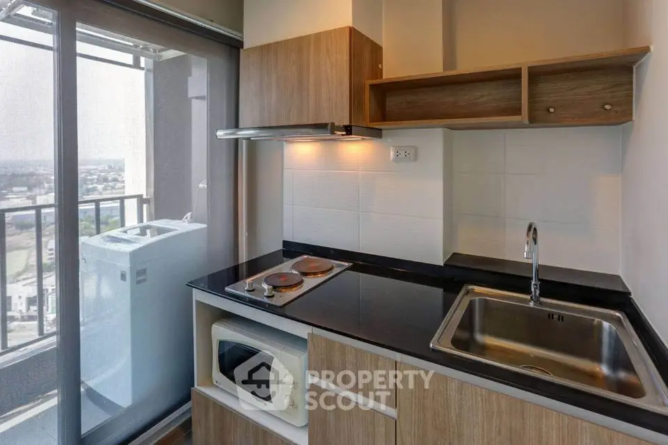 Modern compact kitchen with balcony view, featuring sleek appliances and stylish cabinetry.
