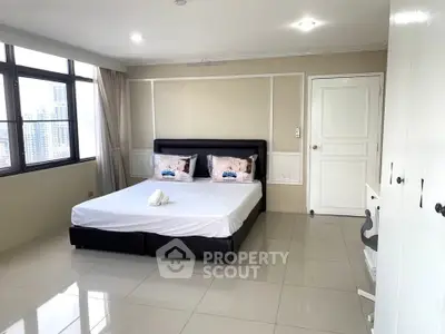 Spacious bedroom with city view and modern furnishings in a high-rise apartment.