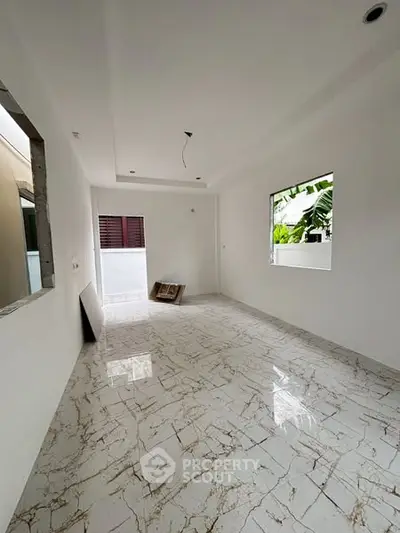 Spacious unfurnished room with marble flooring and large window, ideal for customization.