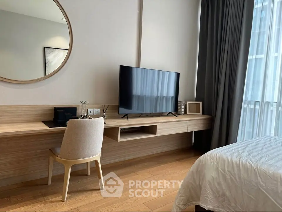 Modern bedroom with sleek TV setup and elegant wooden desk, perfect for urban living.