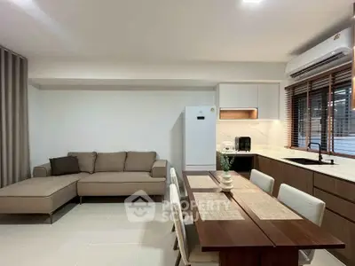 Modern open-layout living room and kitchen with sleek furniture and appliances