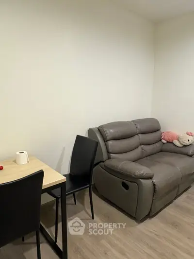 Cozy living room with modern sofa and dining table, perfect for relaxation and small gatherings.