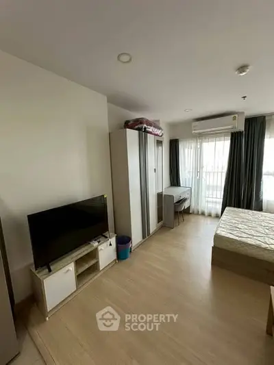 Modern studio apartment with TV, wardrobe, and bed near balcony.