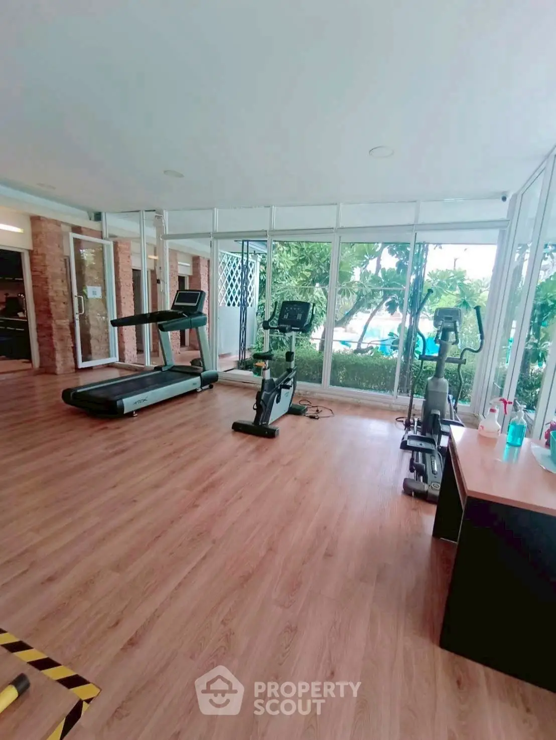 Spacious gym with modern equipment and large windows offering garden views.
