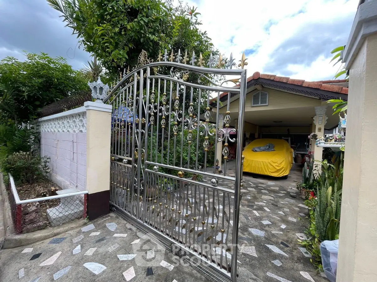 Charming residential entrance with ornate gate and covered parking area