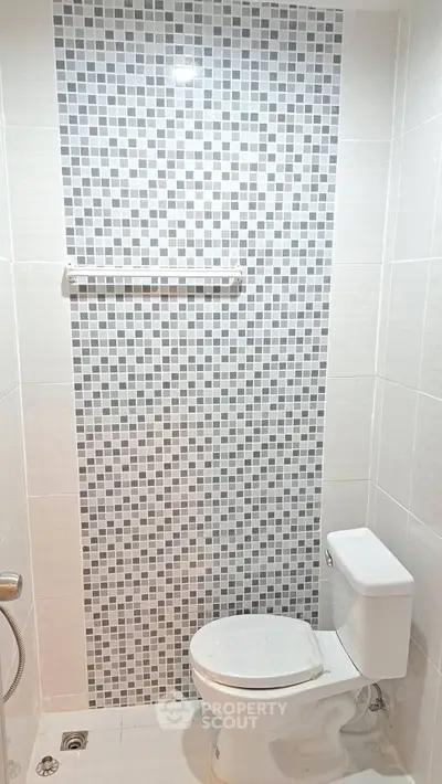Modern bathroom with stylish mosaic tile wall and sleek white fixtures.