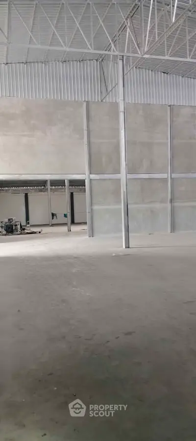 Spacious industrial warehouse with high ceilings and concrete flooring, ideal for storage or manufacturing.