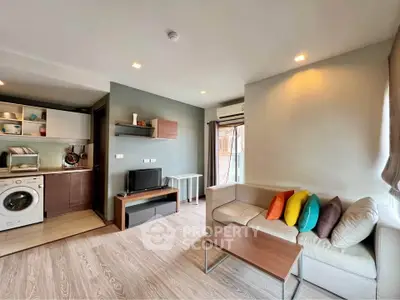 Modern living room with open kitchen, cozy sofa, and vibrant cushions in a stylish apartment.