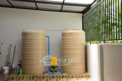 Outdoor water storage tanks in a modern residential setting with tiled flooring and green surroundings.