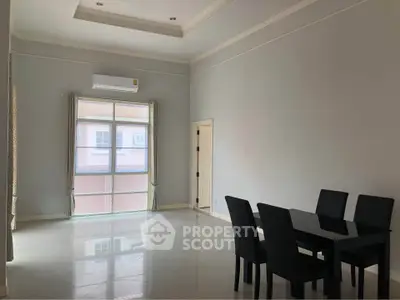 Spacious dining area with modern table and chairs, large window, and air conditioning unit.