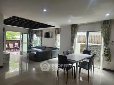 Spacious modern living room with dining area and large windows leading to a patio.