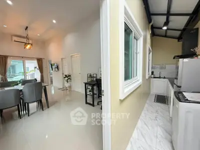 Modern open-plan living and dining area with adjacent sleek kitchen in a stylish home.