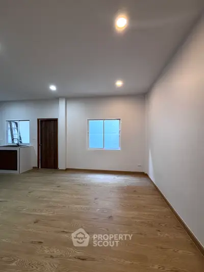 Spacious empty room with wooden flooring and bright lighting, ideal for customization.