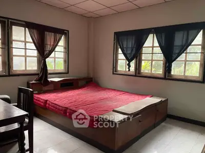 Cozy bedroom with large windows and red bedding, perfect for natural light lovers.