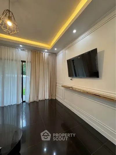 Elegant living room with modern lighting, large TV, and floor-to-ceiling curtains opening to a garden view.