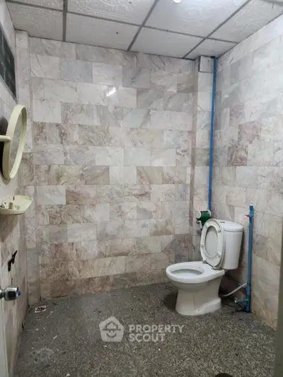 Spacious bathroom with tiled walls and modern toilet in real estate property.