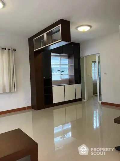 Spacious modern living room with built-in shelving and glossy tiled floor