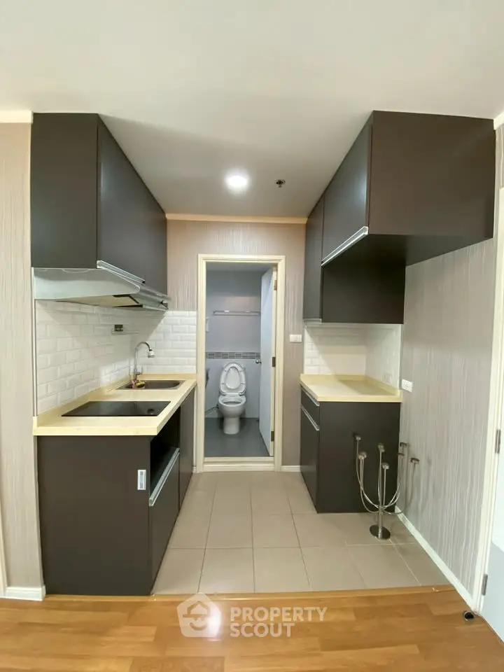 Modern kitchen with sleek cabinetry and open layout leading to a compact bathroom.