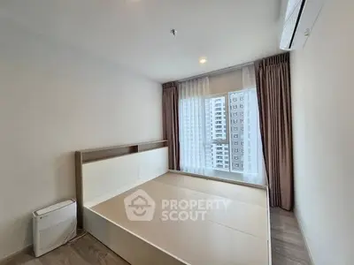 Modern bedroom with large window and city view, featuring a minimalist bed frame and air conditioning.