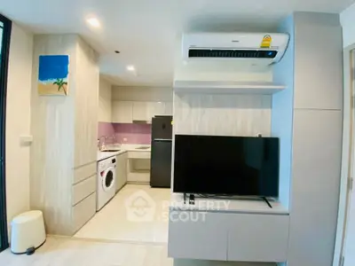 Modern living room with open kitchen, featuring sleek appliances and stylish decor.