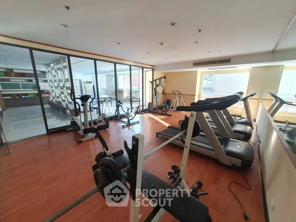 Spacious gym with modern equipment and wooden flooring in a residential building.