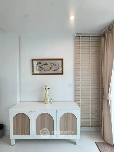 Stylish interior with elegant cabinet and wall art in a bright, modern living space.