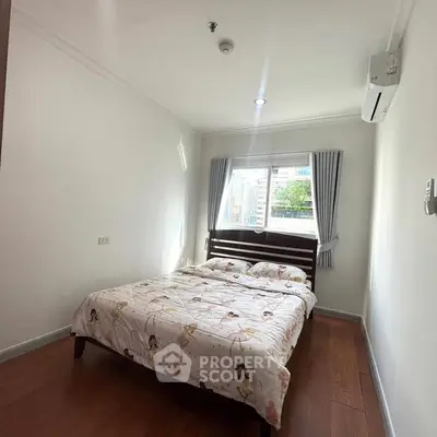 Cozy bedroom with wooden flooring, large window, and air conditioning unit.