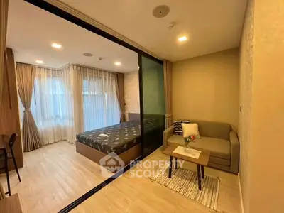 Modern studio apartment with cozy living area and bedroom separated by glass partition.