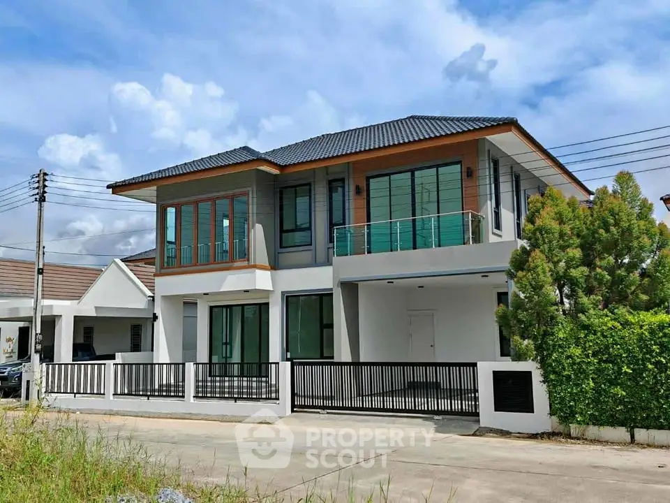 Modern two-story house with large windows and balcony in a suburban neighborhood.